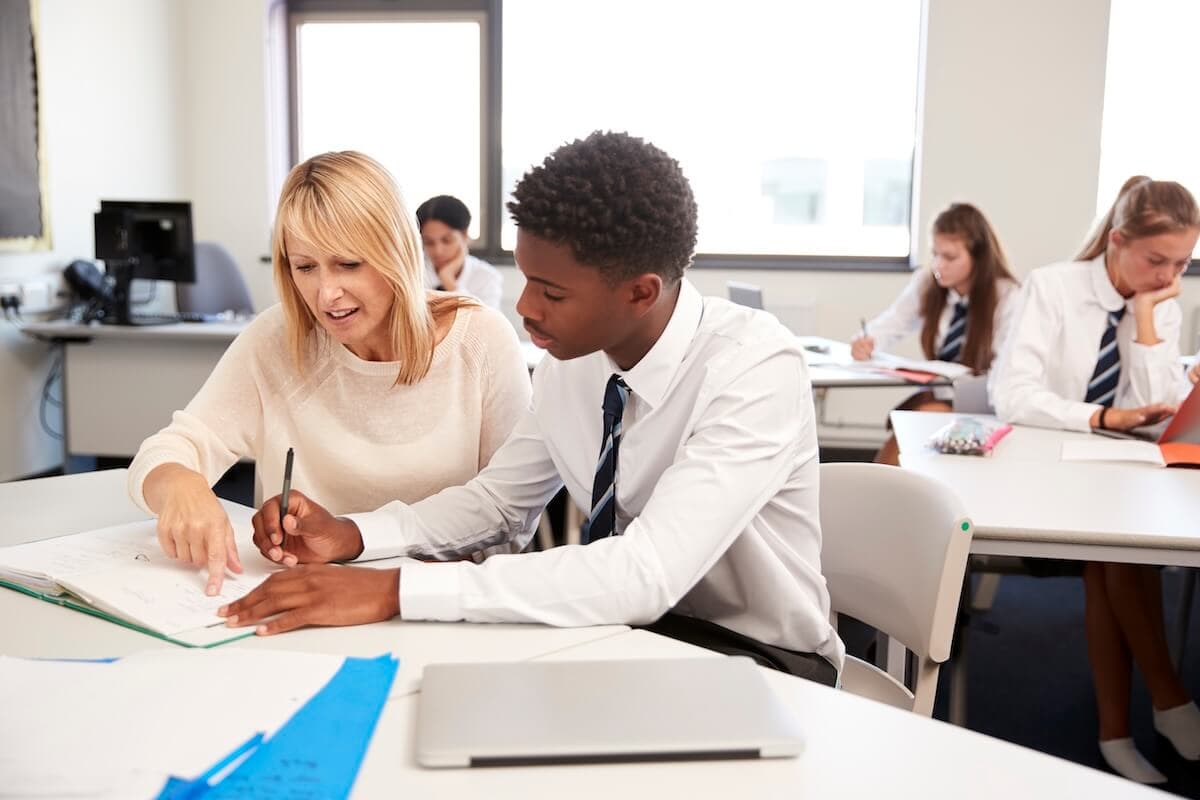 Student sat in classroom getting teacher to help with school work